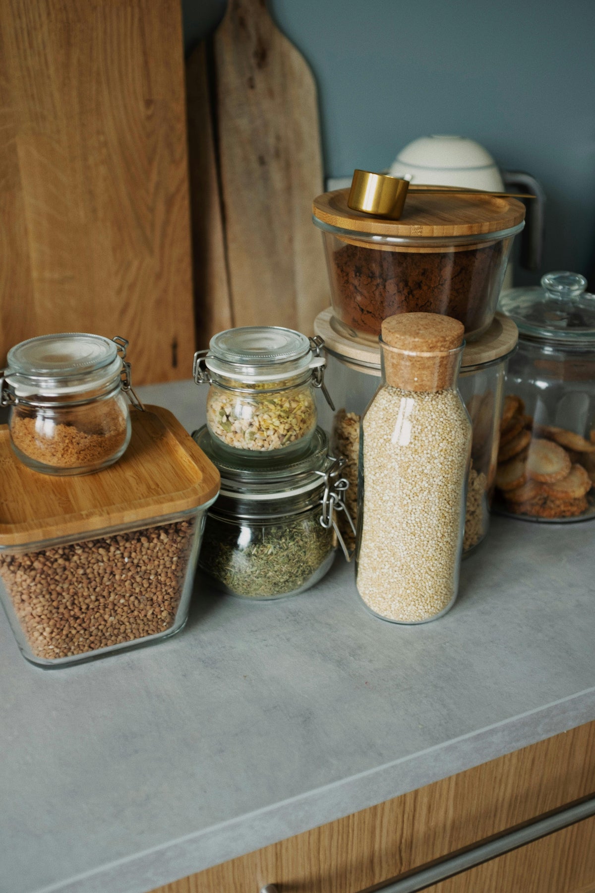Reusable glass storage jars and containers with wooden lids on a light gray counter