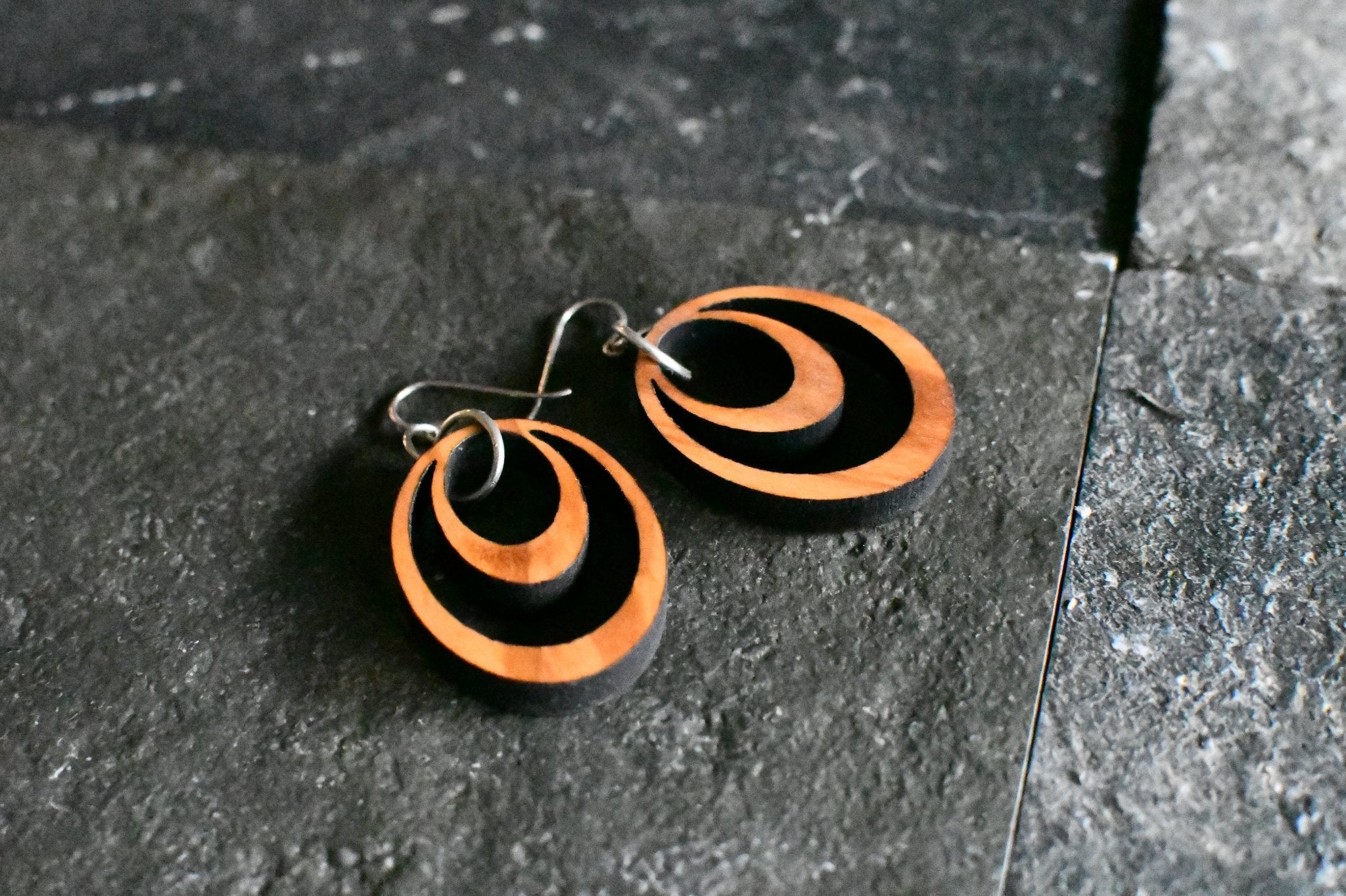 Pair of wooden hoop earrings on a dark stone surface