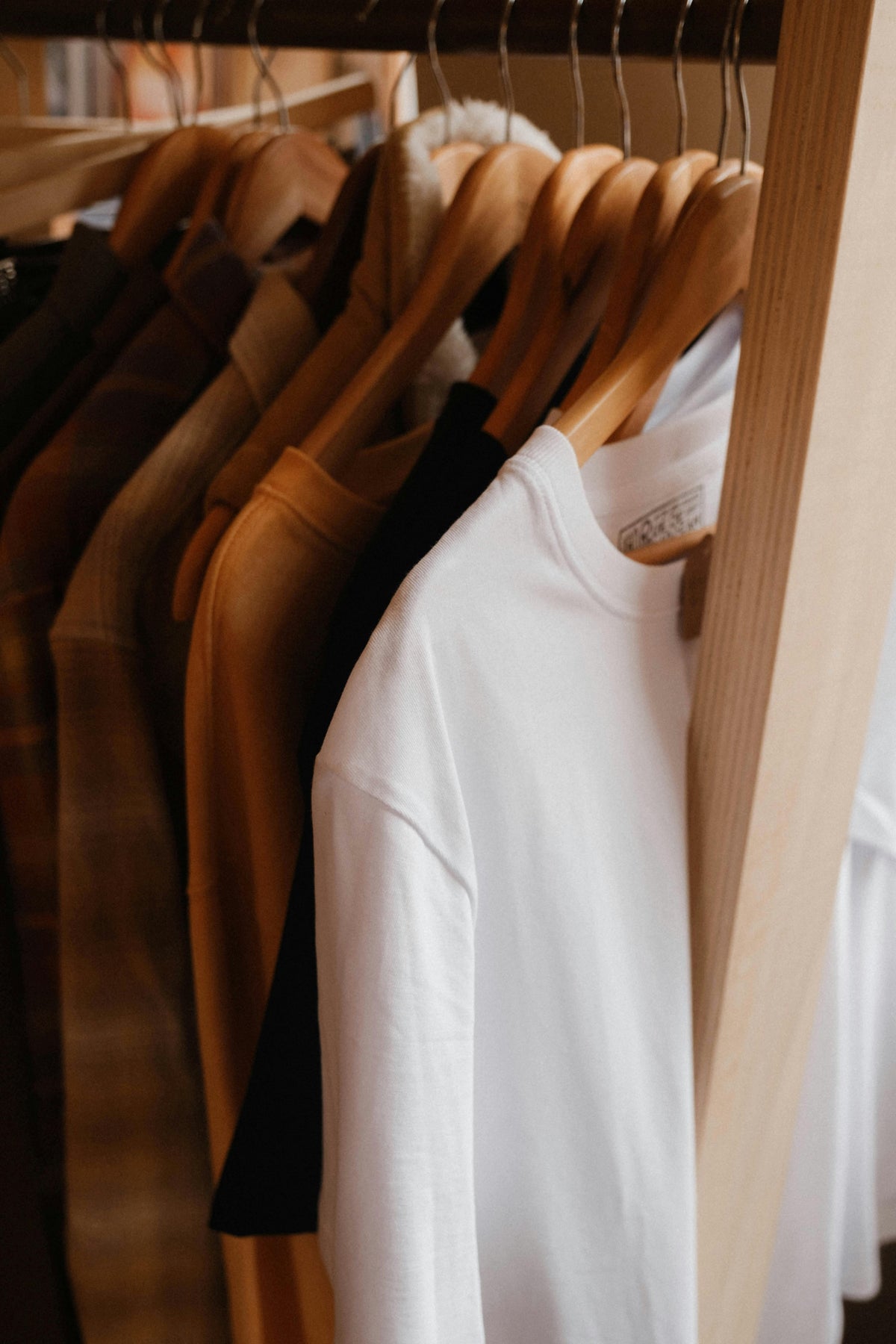 Clothing rack with shirts of various types placed on wooden hangers.