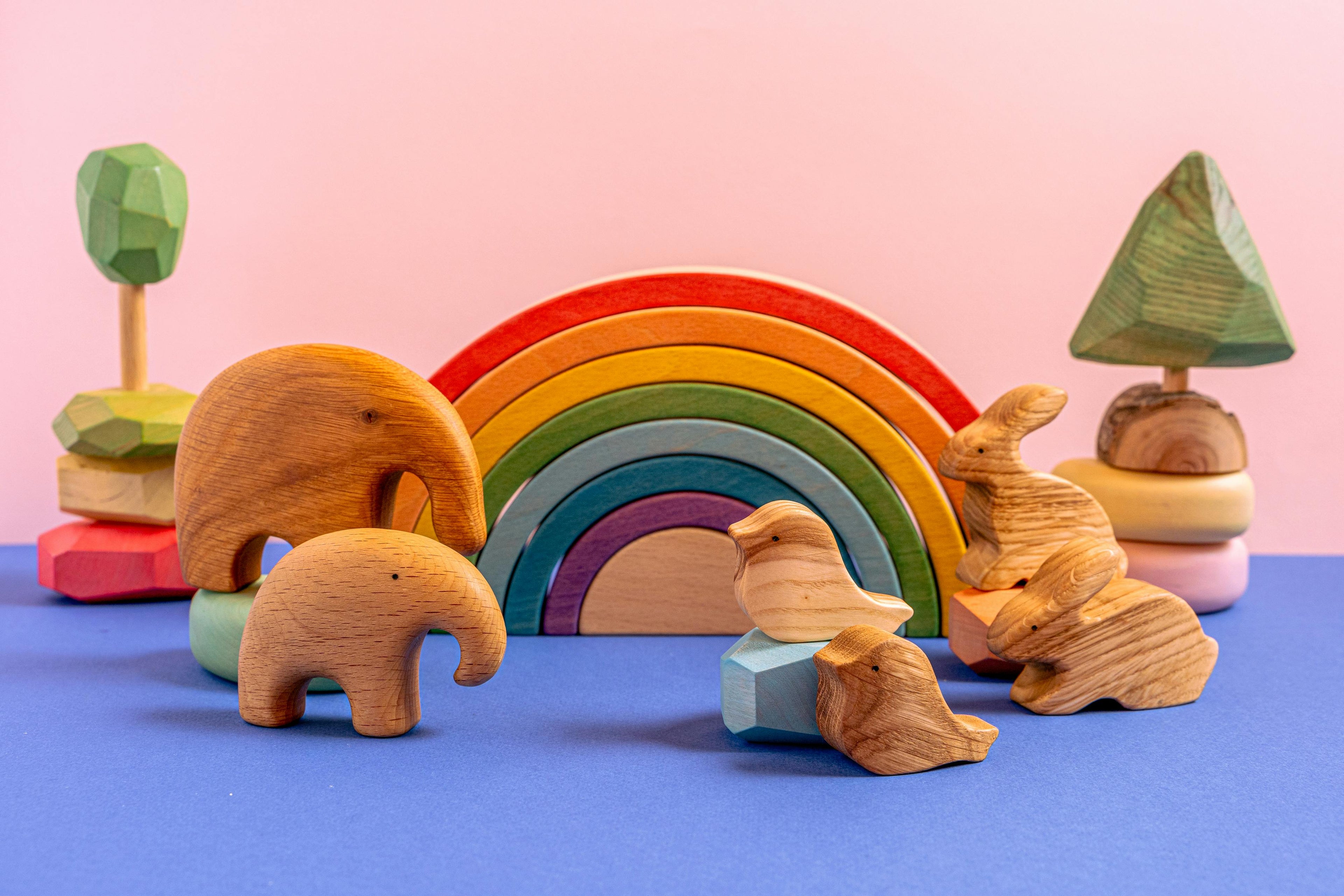 Set of wooden toys including a rainbow stacker and animal figures: elephants, trees, birds and rabbits
