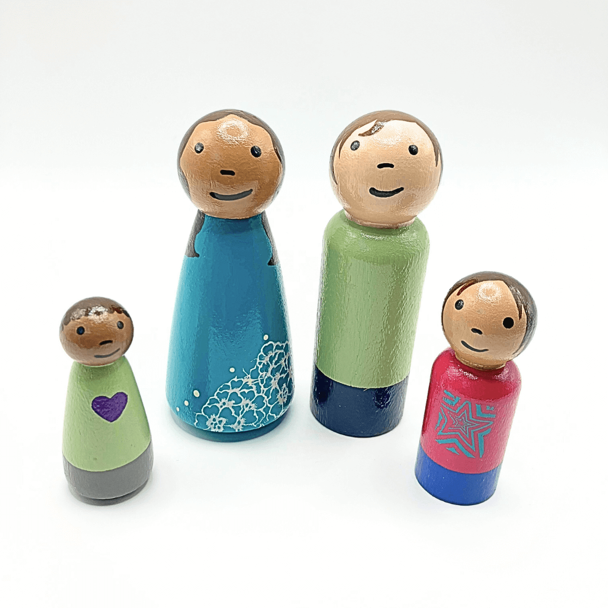 Set of four wooden peg dolls with different colored outfits on a white background