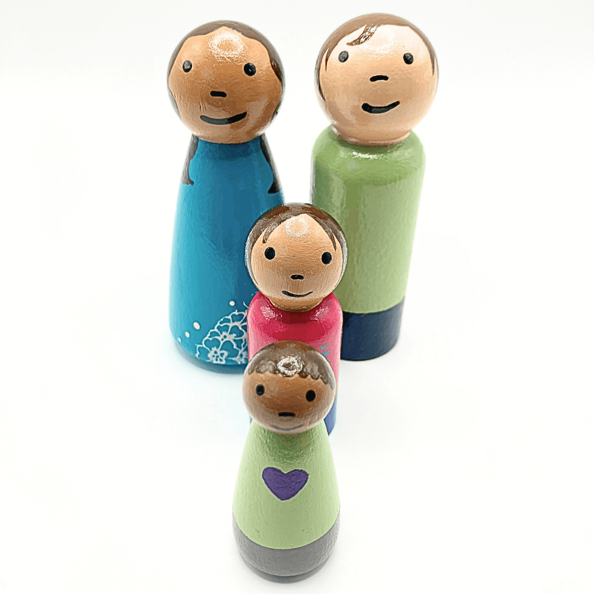 Set of wooden family figurines with different colored dresses on a white background