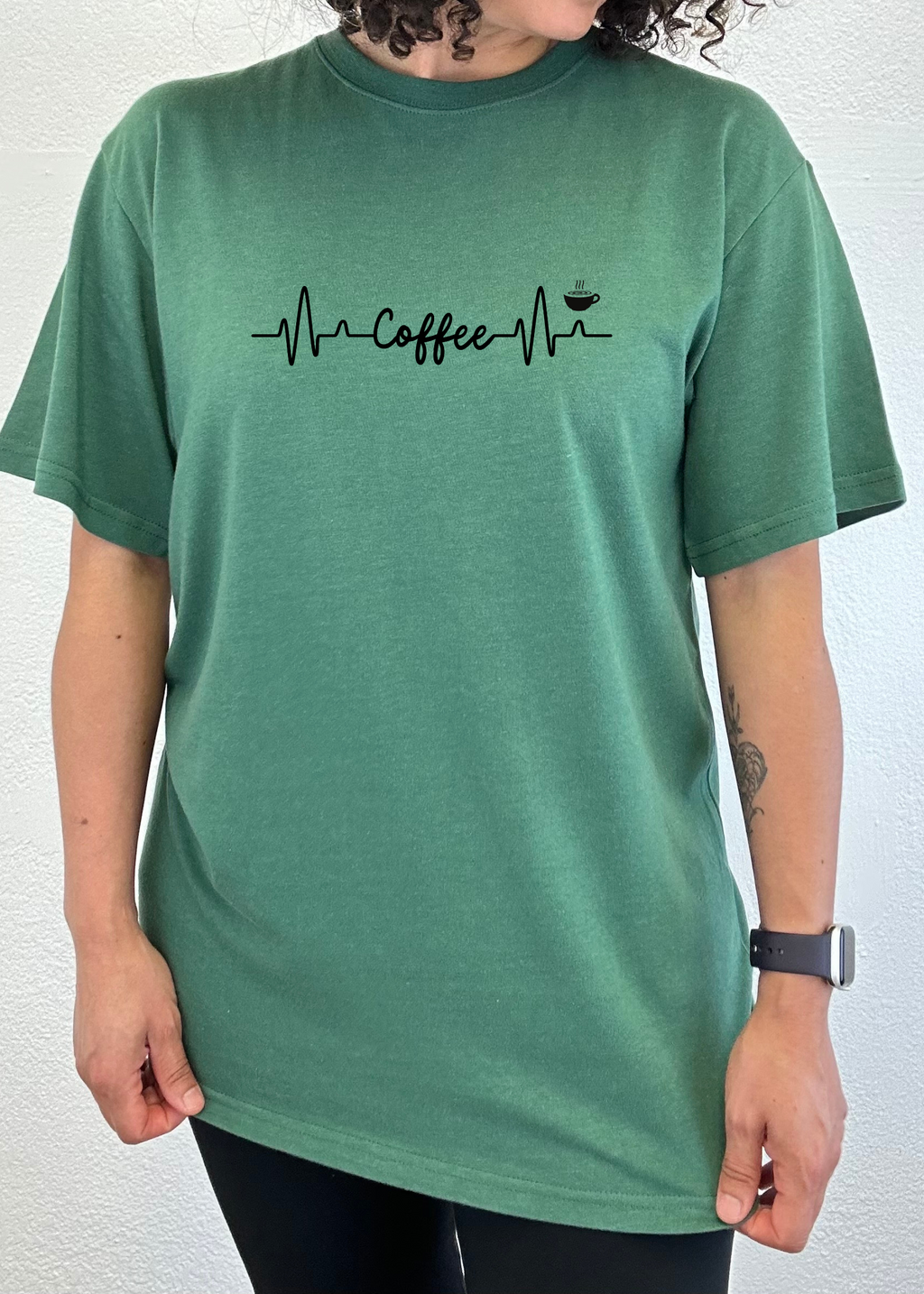 Person wearing a green t-shirt with a coffee-themed design on a white background