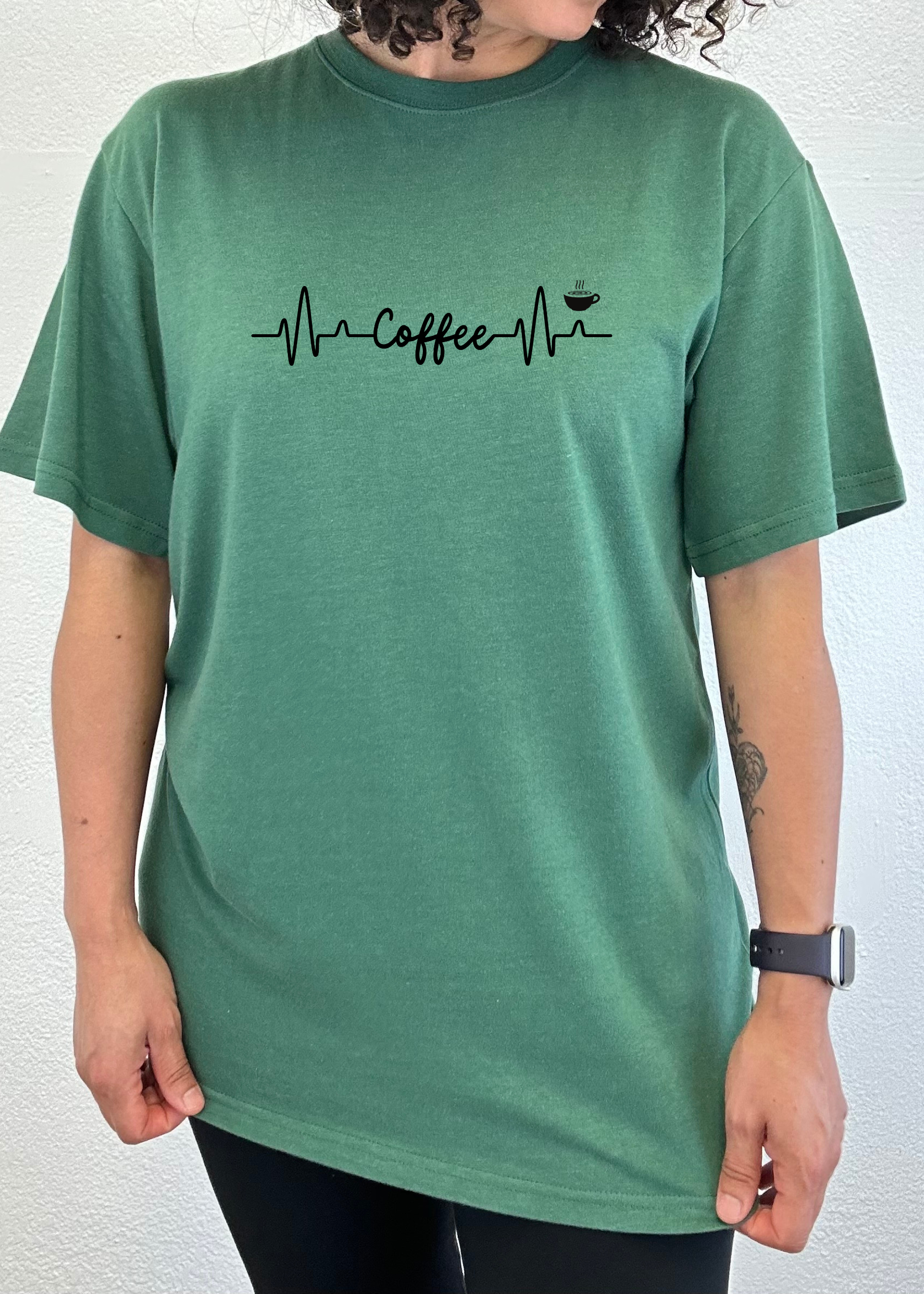 Person wearing a green t-shirt with a coffee-themed design on a white background