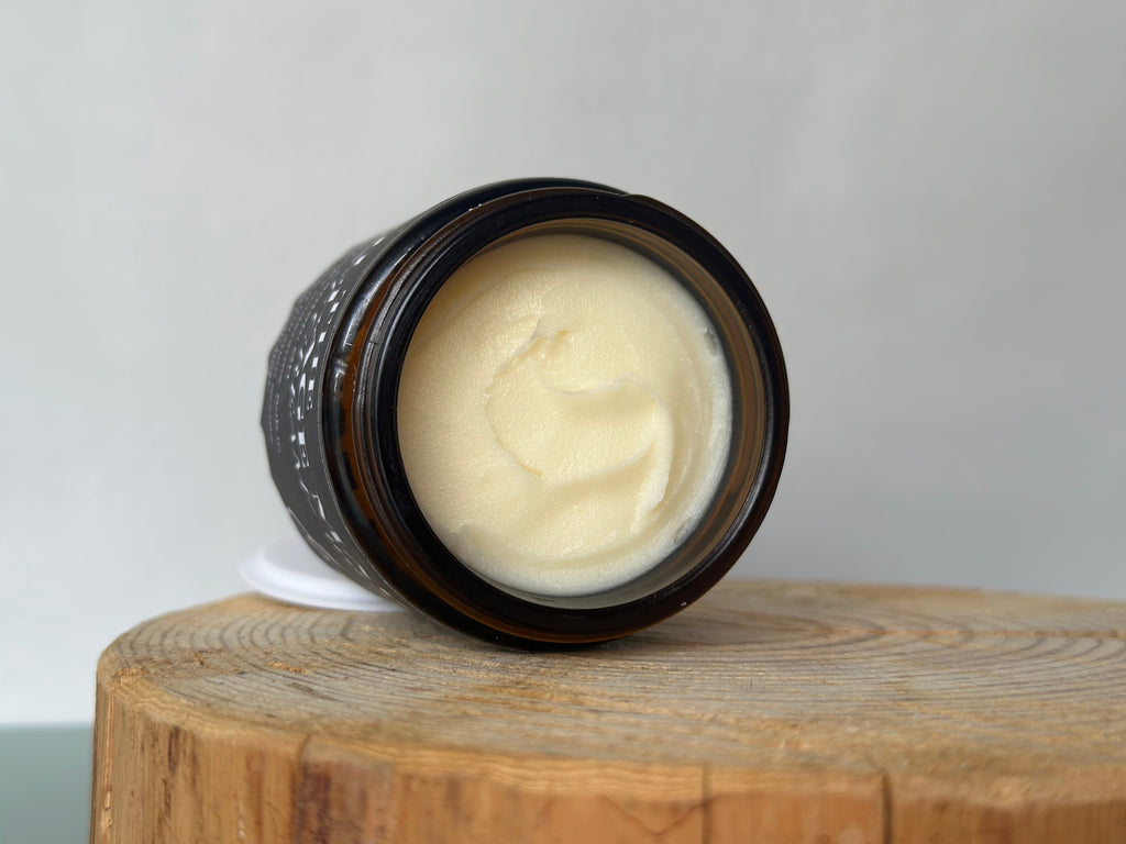 Jar of cream deodorant on a wooden block with a white background