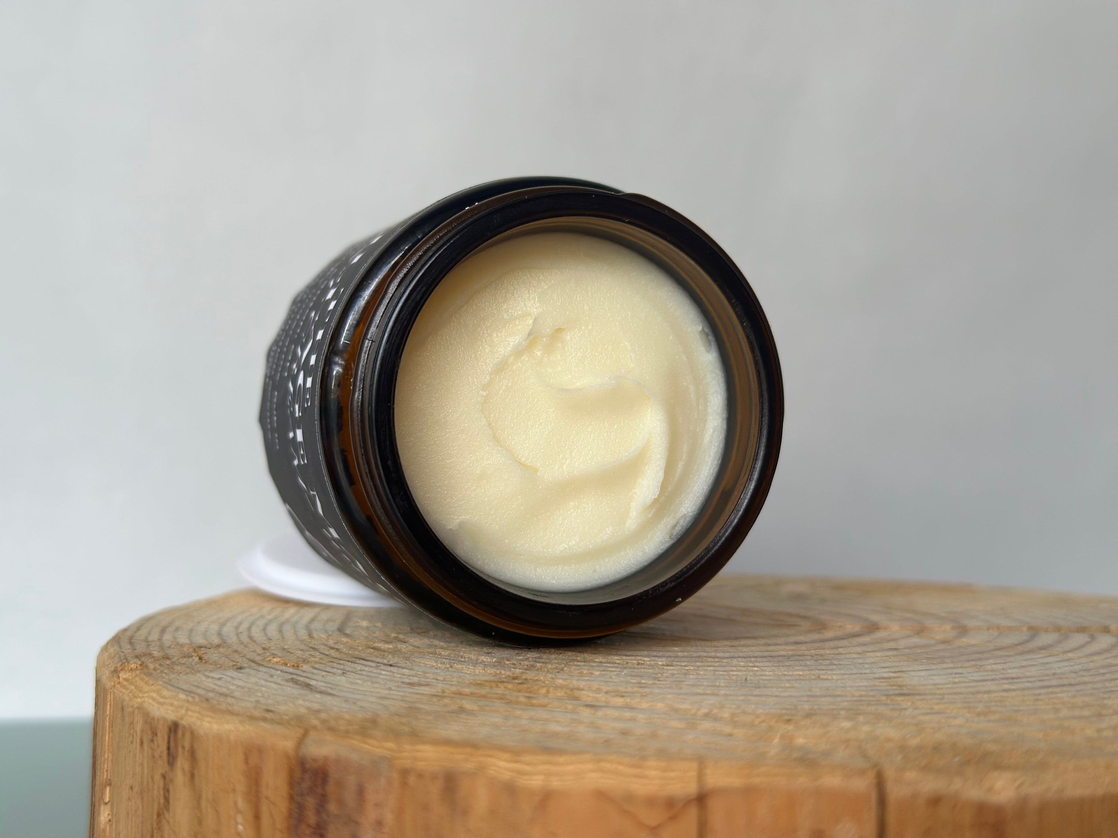 Jar of cream deodorant on a wooden block with a white background