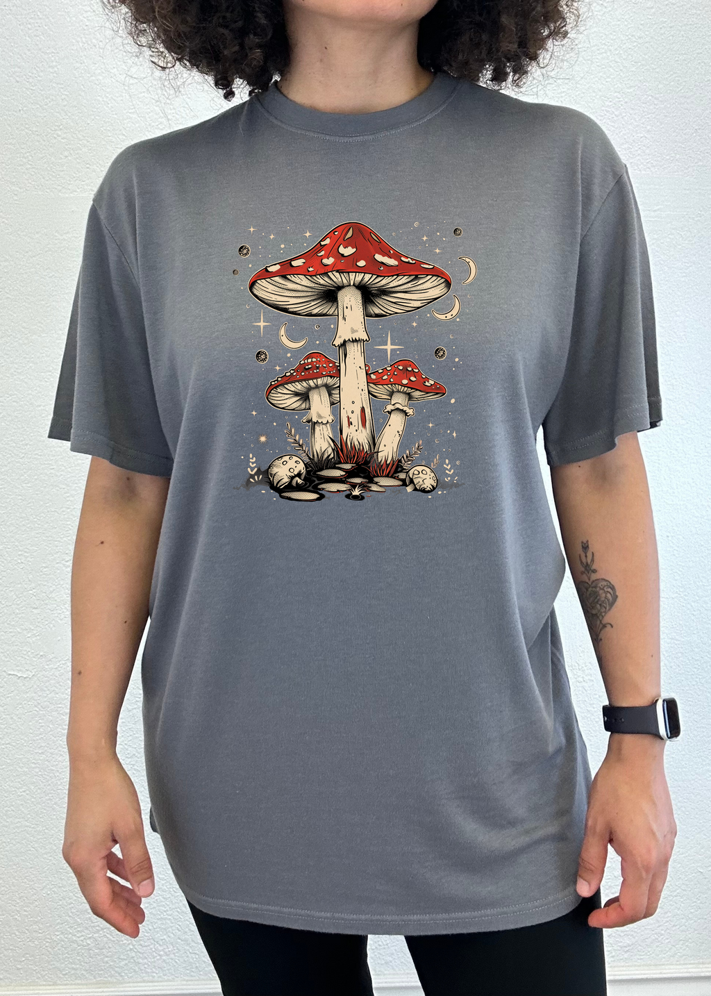 Person wearing a gray t-shirt with a mushroom design on a white background