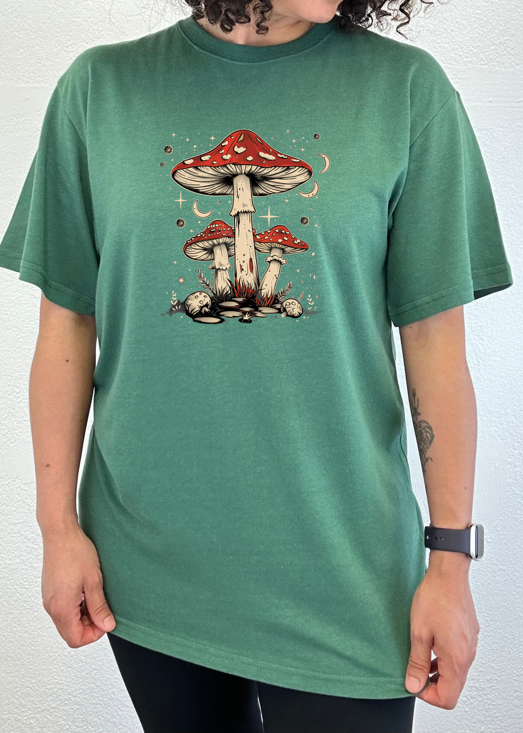 Person wearing a green t-shirt with a mushroom design on a white background