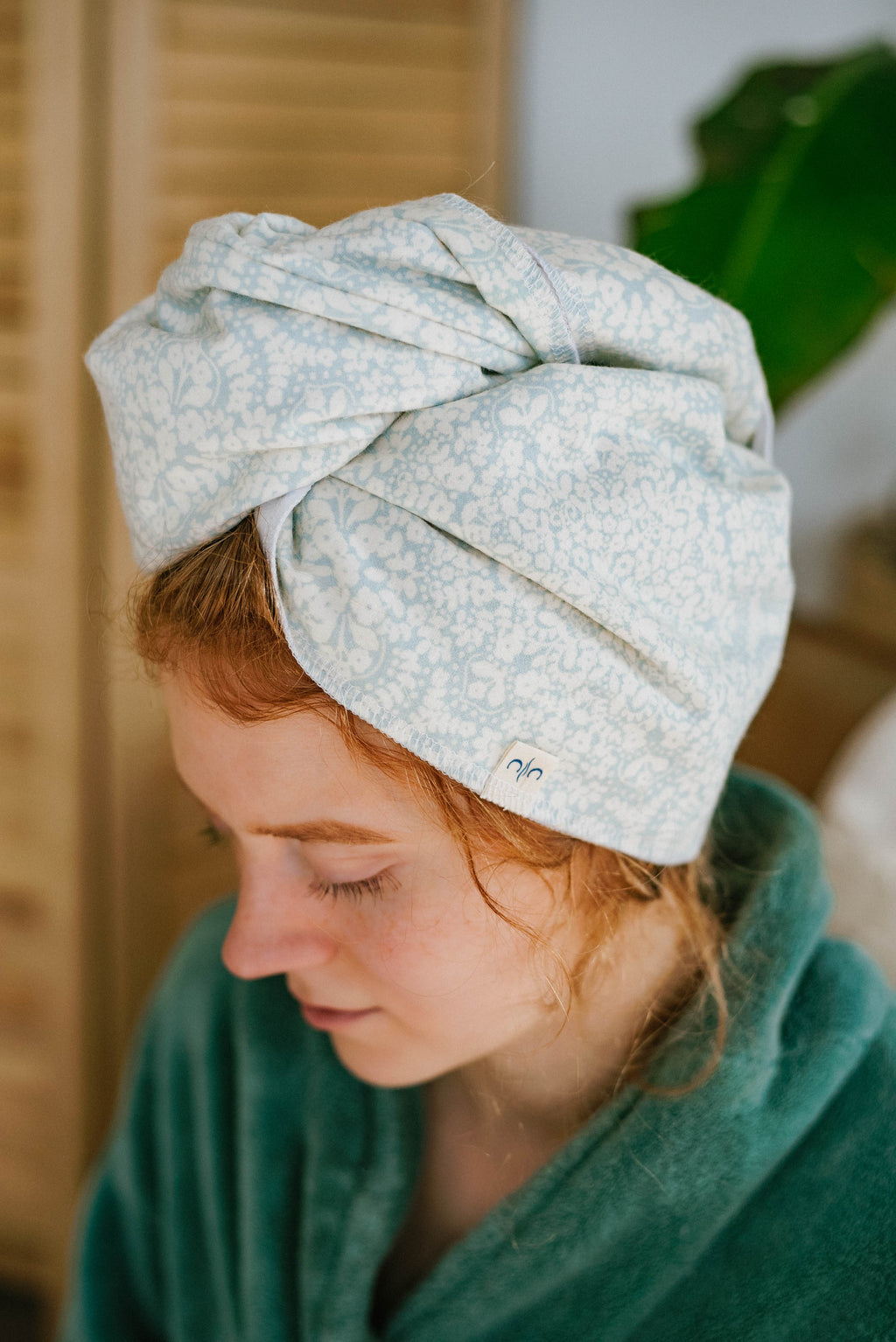 Person wearing a light blue patterned towel on their head with a blurred background