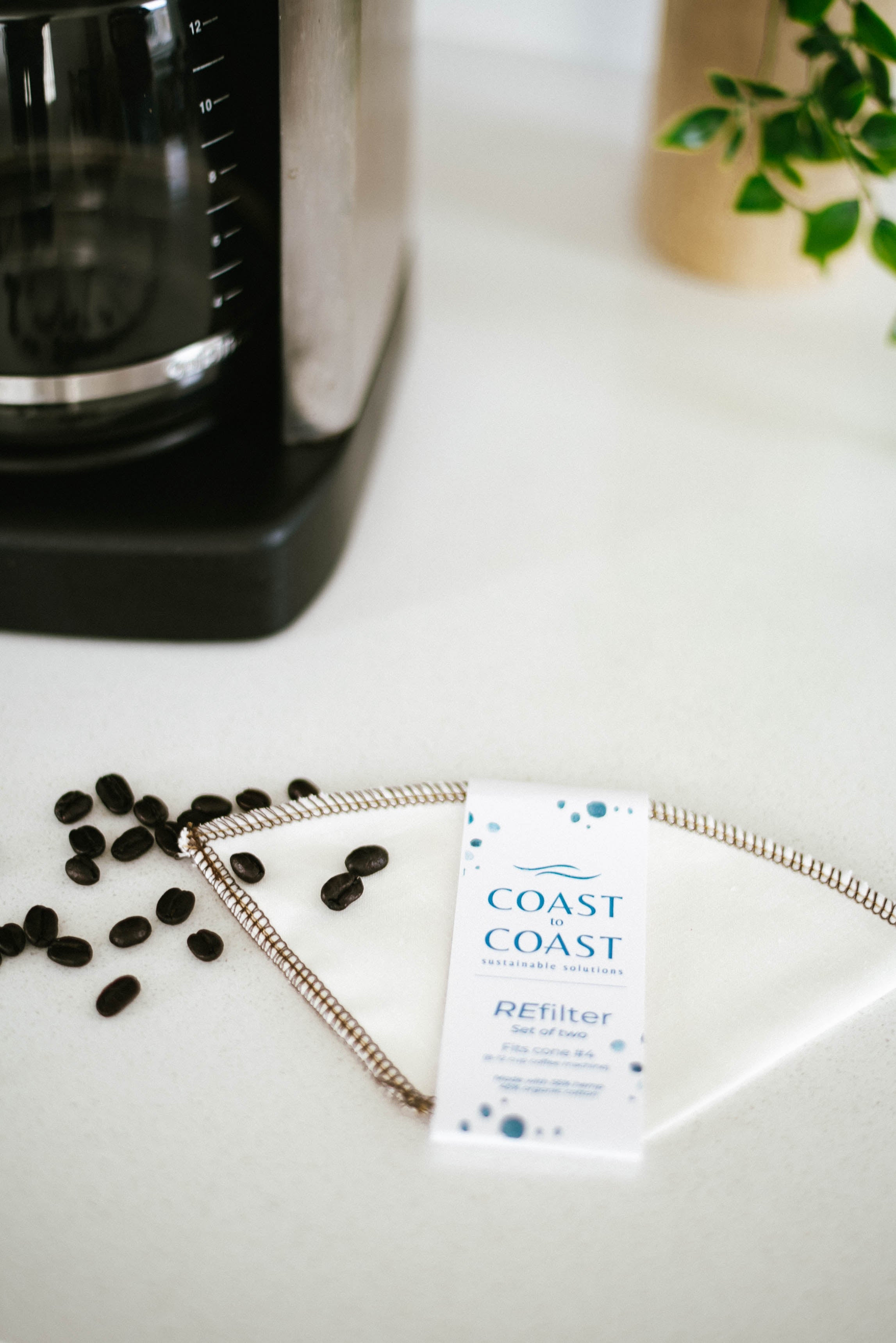 Coast to Coast Refilter package on a kitchen counter with coffee beans and a coffee maker.