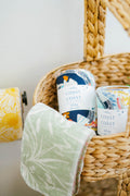 Wicker basket with 'Coast to Coast' -branded products and a green towel.