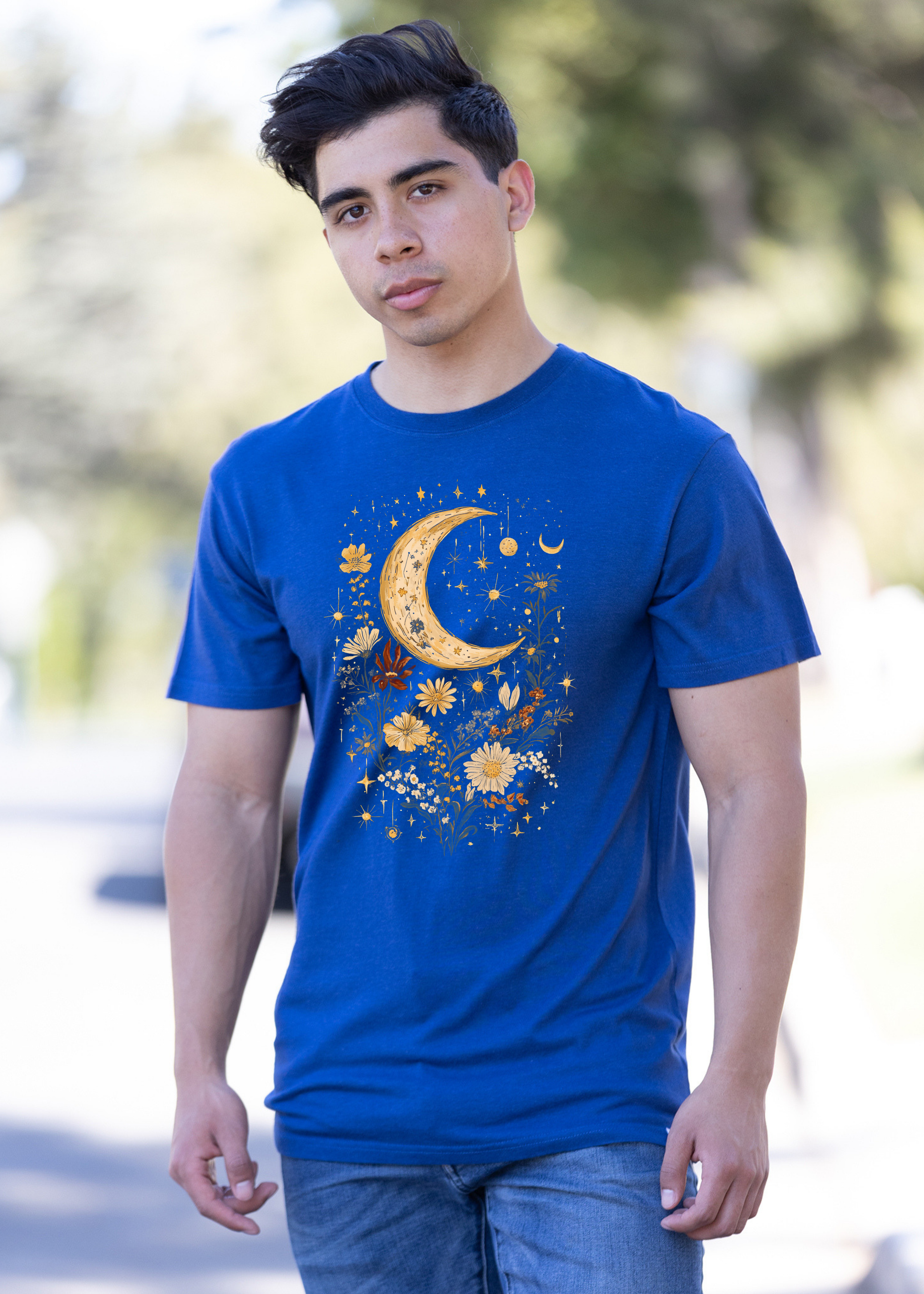 Person wearing a blue t-shirt with a moon and floral design outdoors.