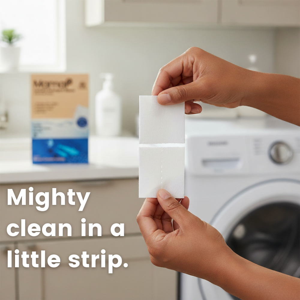 Person holding a white laundry detergent strip with a washing machine in the background