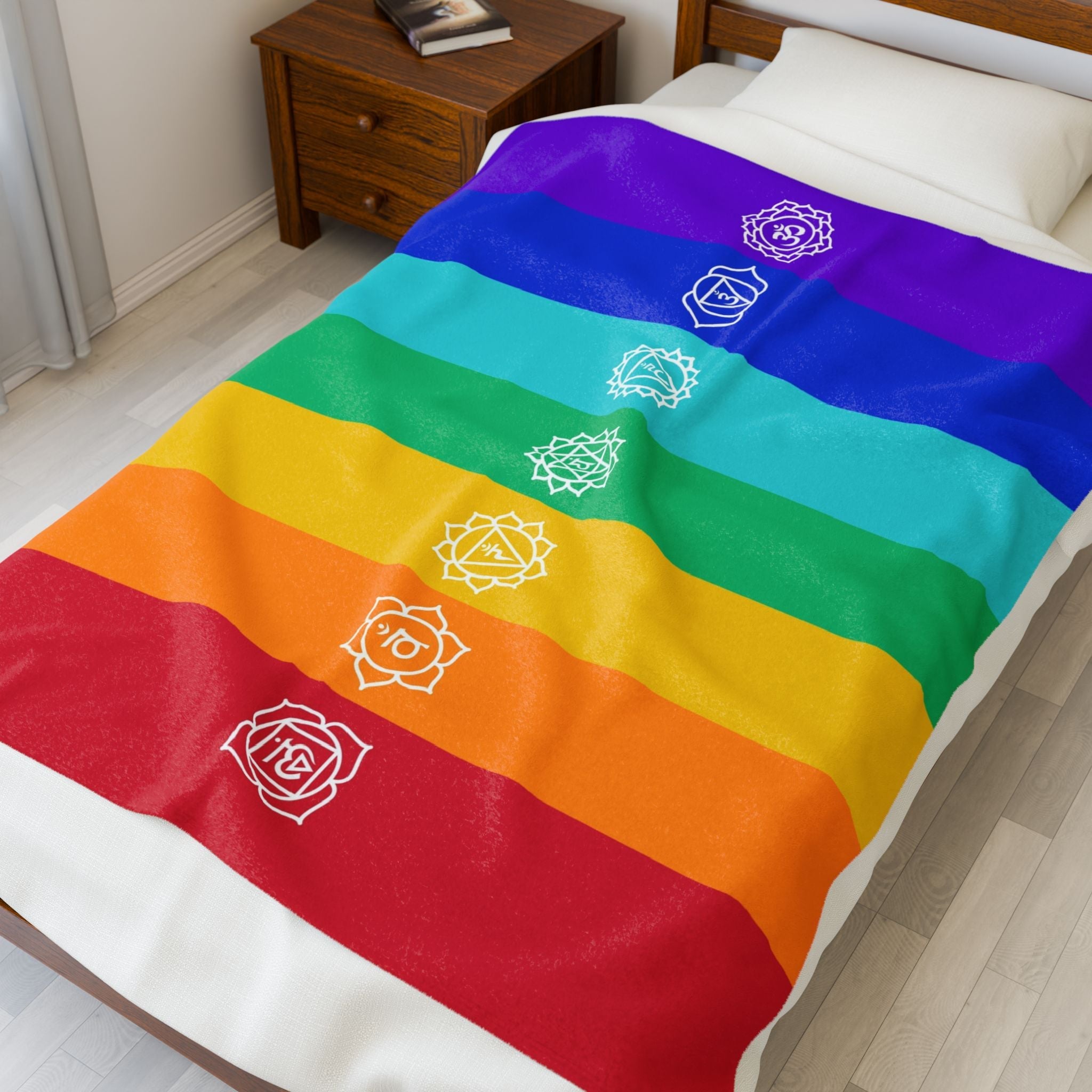 Colorful rainbow-themed blanket with white chakra symbols on a bed in a bedroom.