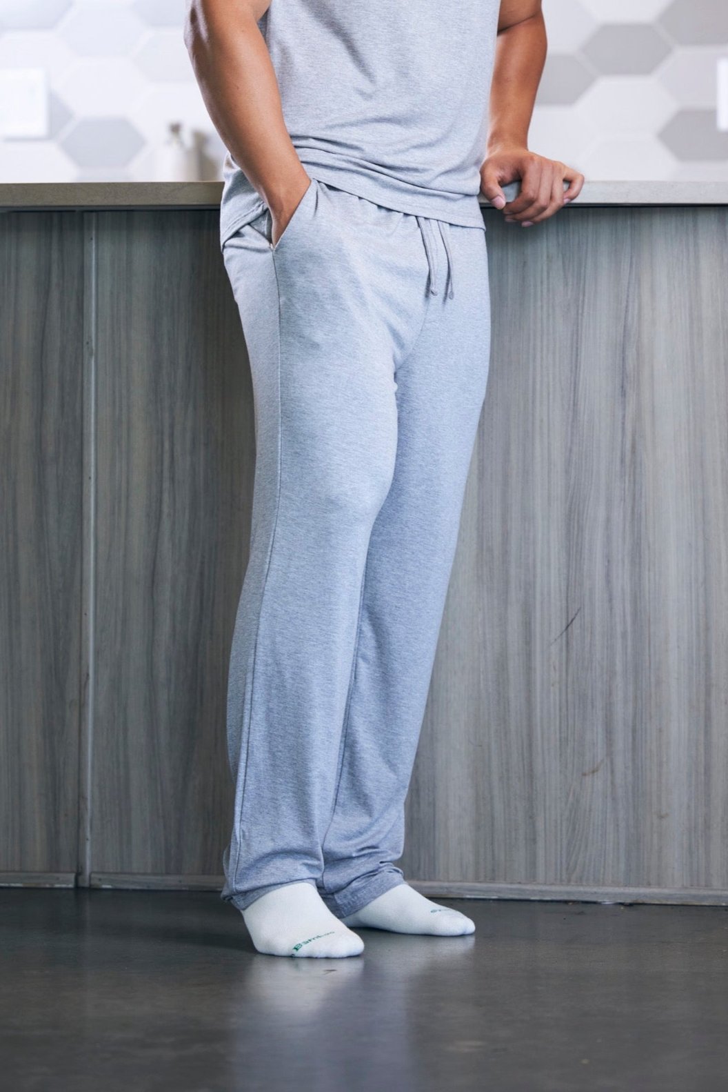 Person wearing light blue sweatpants and white socks standing in a kitchen.