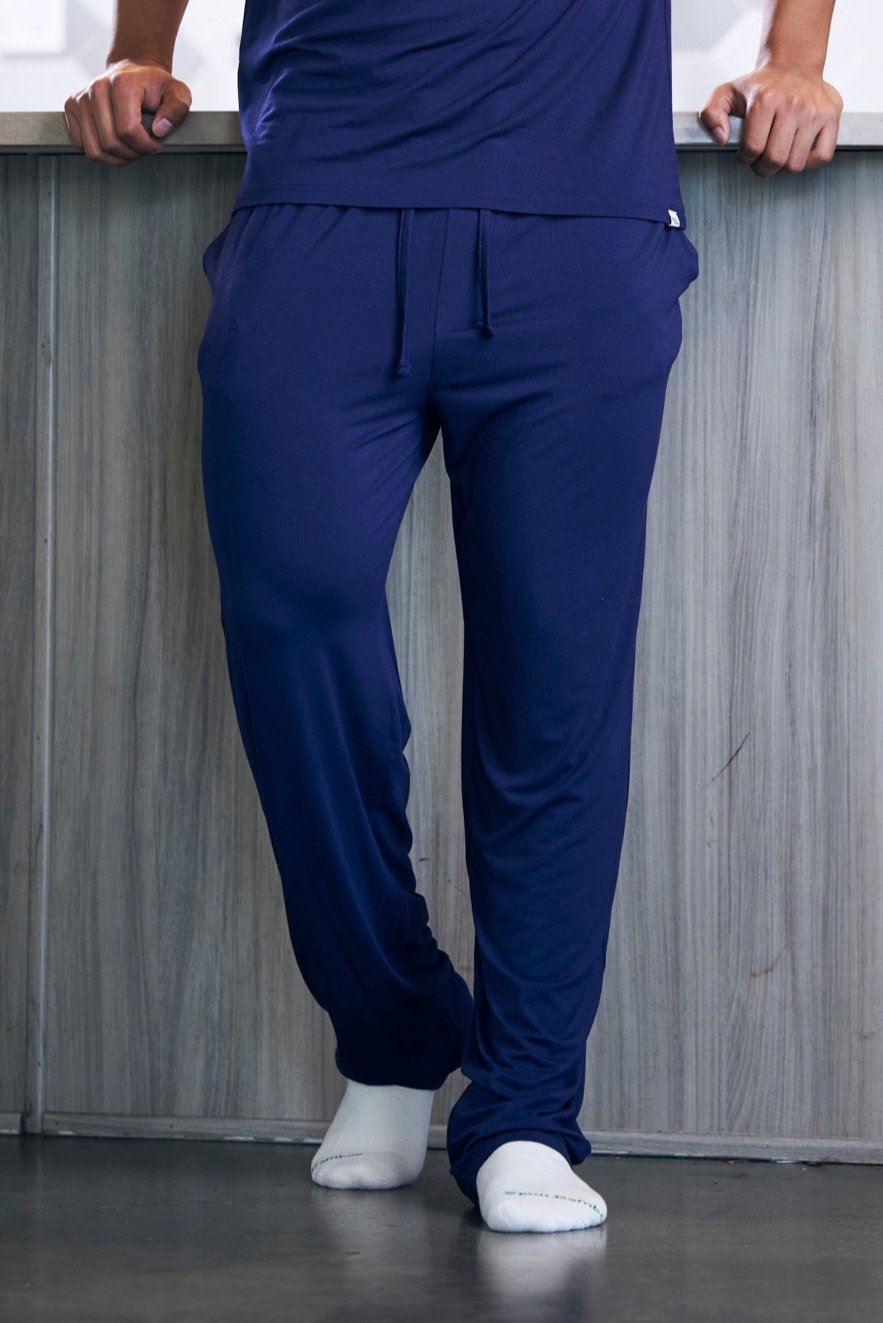 Person wearing blue pants standing against a neutral background