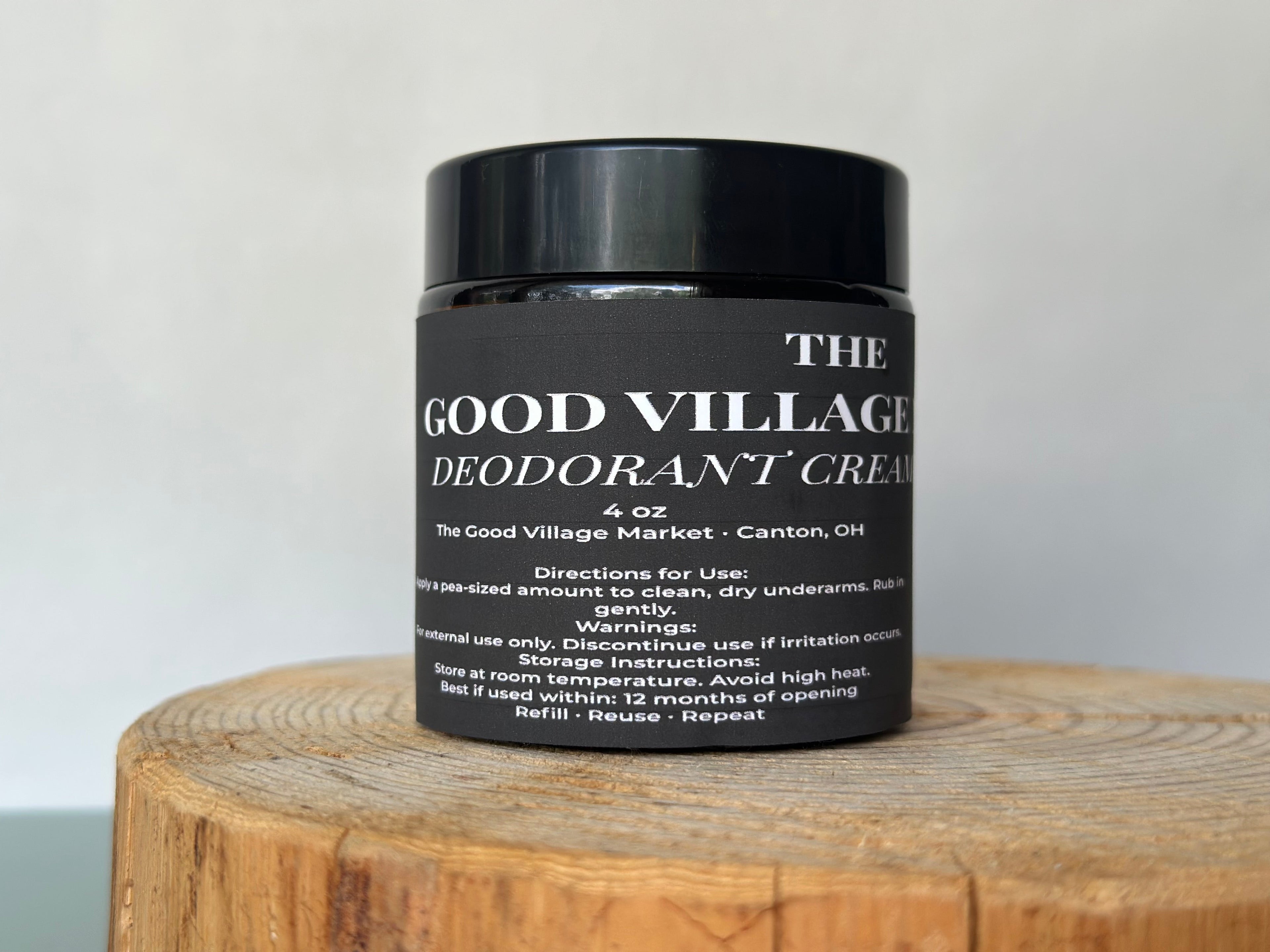 Jar of The Good Village Deodorant Cream on a wooden block with a light gray background