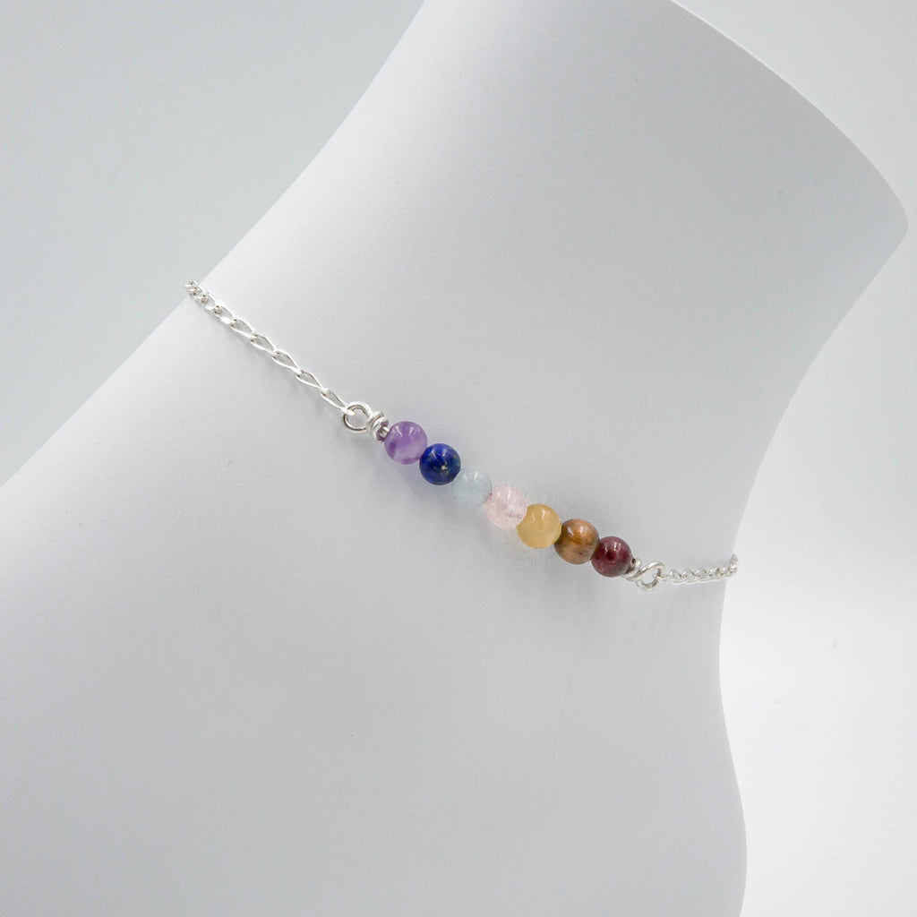 Multicolored bead anklet on a mannequin leg against a white background
