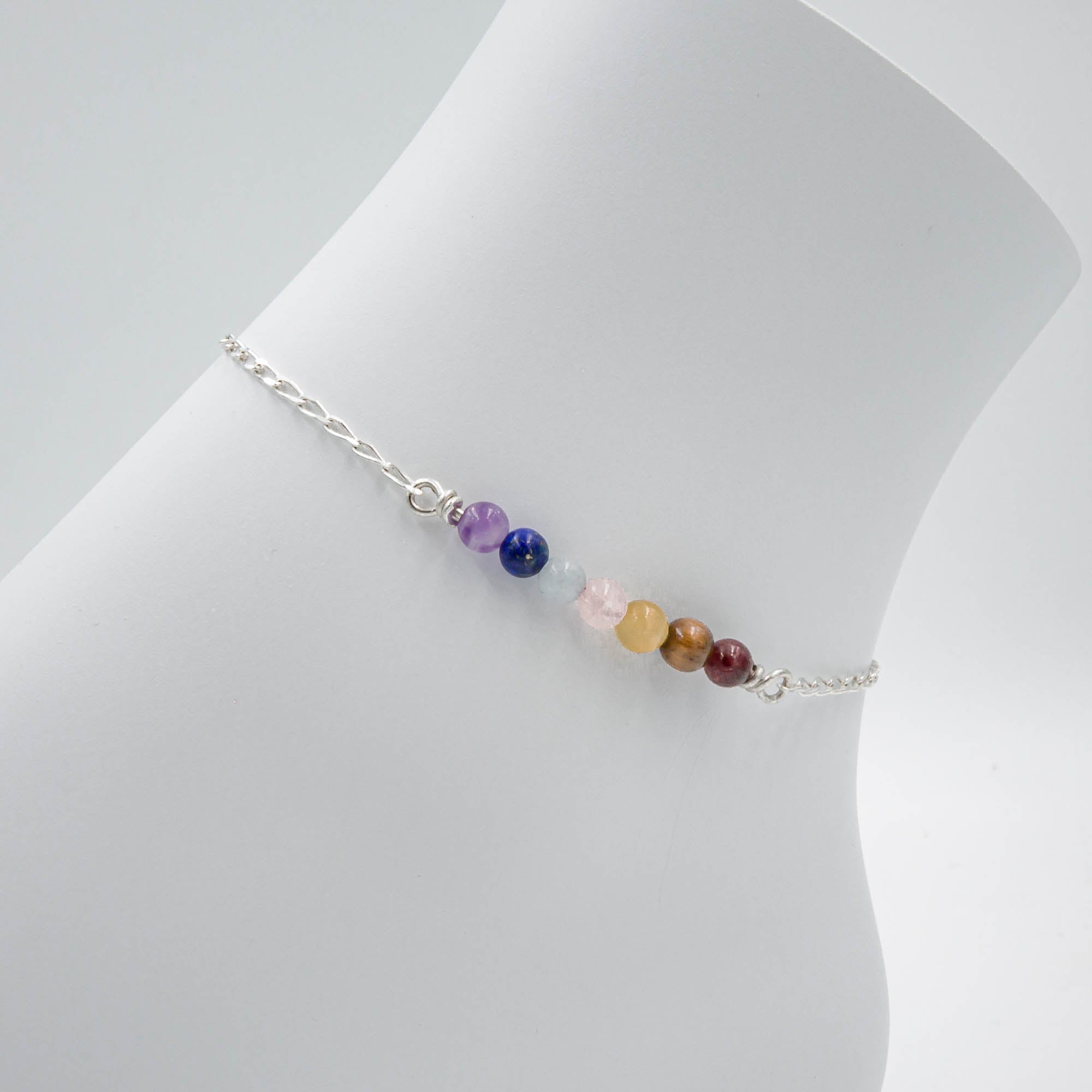 Multicolored bead anklet on a mannequin leg against a white background