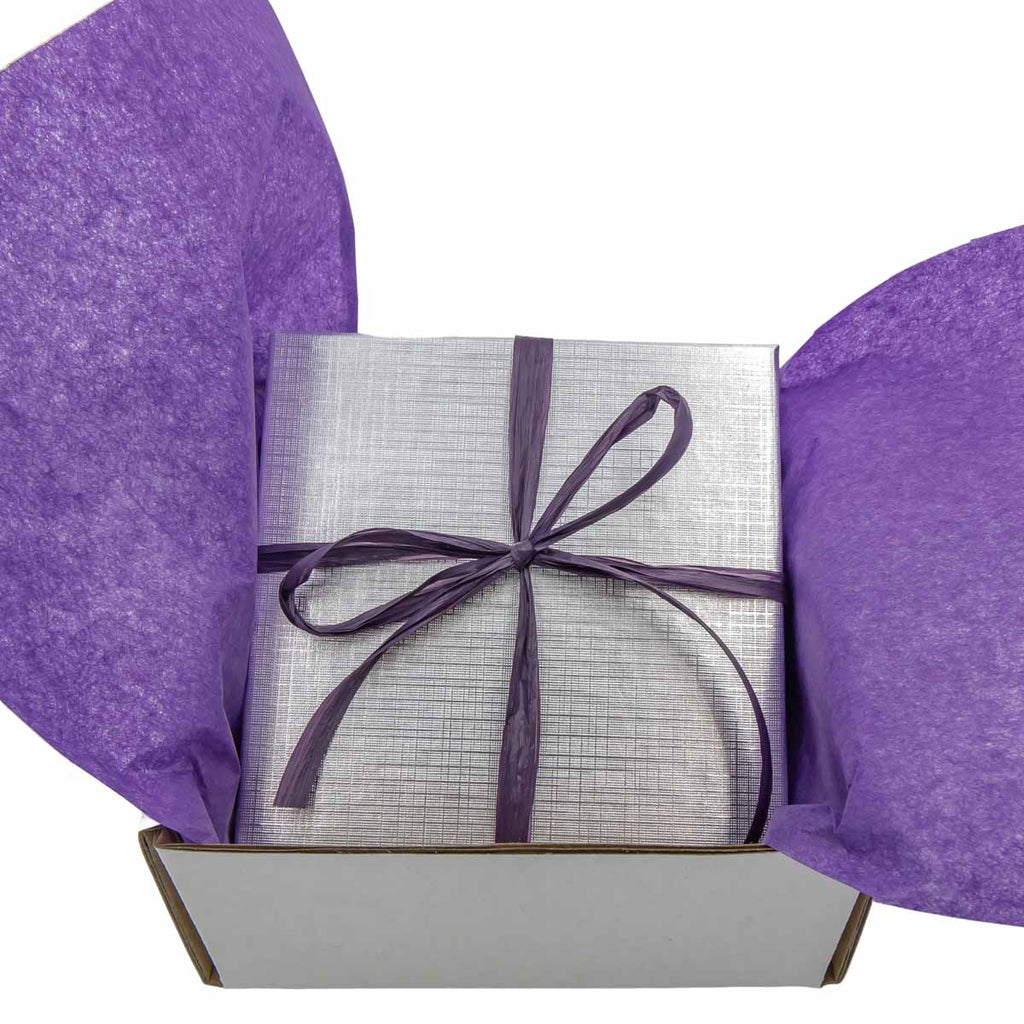 Gift box with silver wrapping paper and purple ribbon on a white background