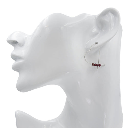 Silver heart shaped earring on a white mannequin ear with a plain background