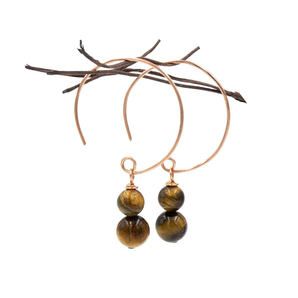 Gold hoop earrings with tiger eye stones on a white background