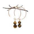 Gold hoop earrings with tiger eye stones on a white background