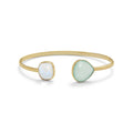 Gold bangle with two gemstones, one white and one light green, on a white background