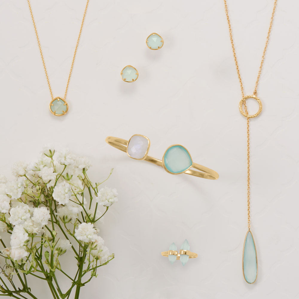 Gold jewelry with green gemstones on a light background