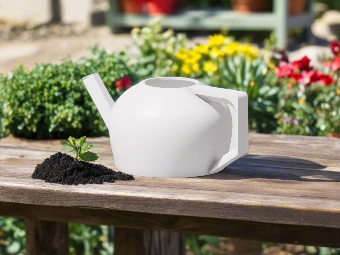 White watering can on a wooden table with soil and a small plant in a garden setting