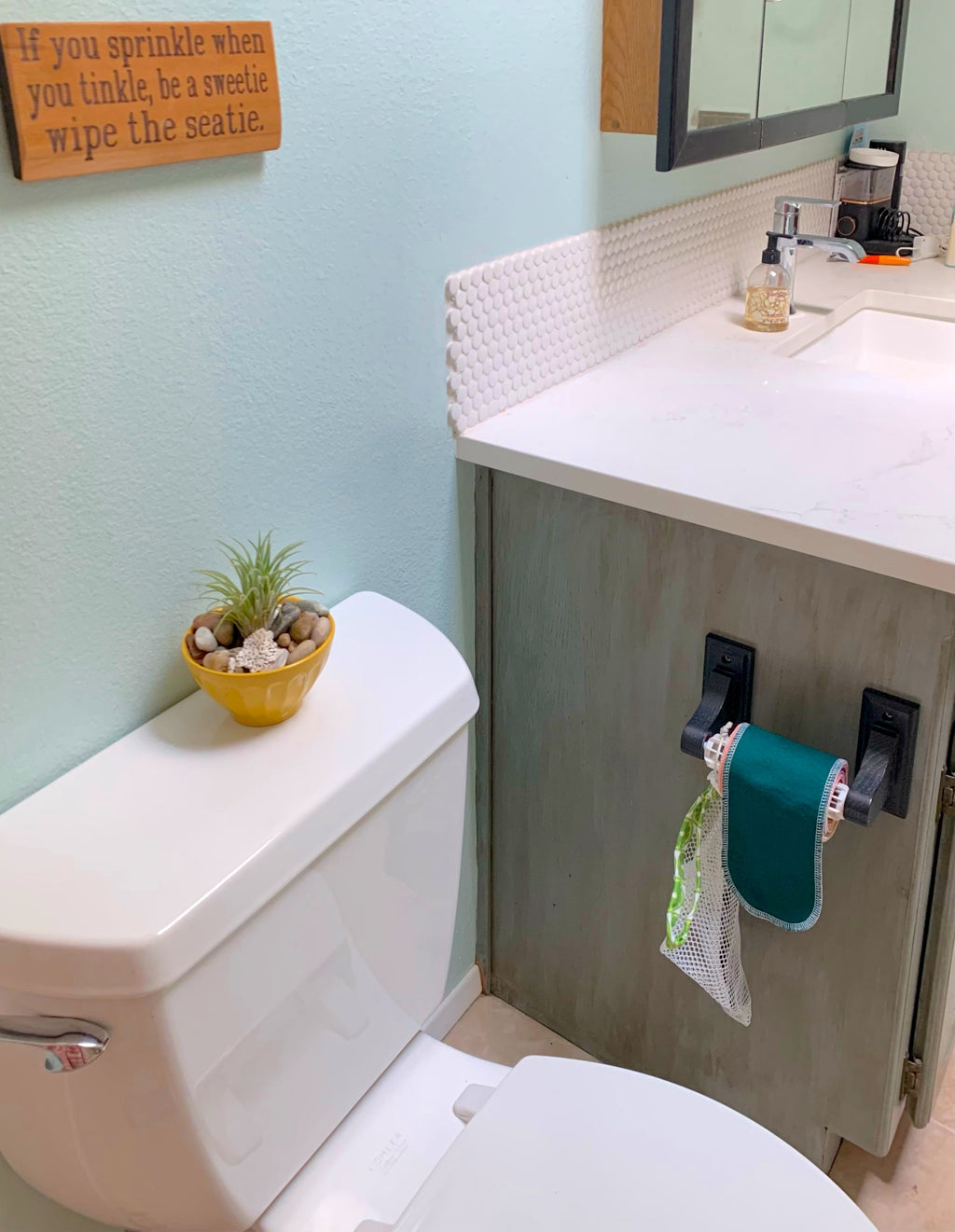 Bathroom with toilet, sink, and decorative elements on a light blue wall.