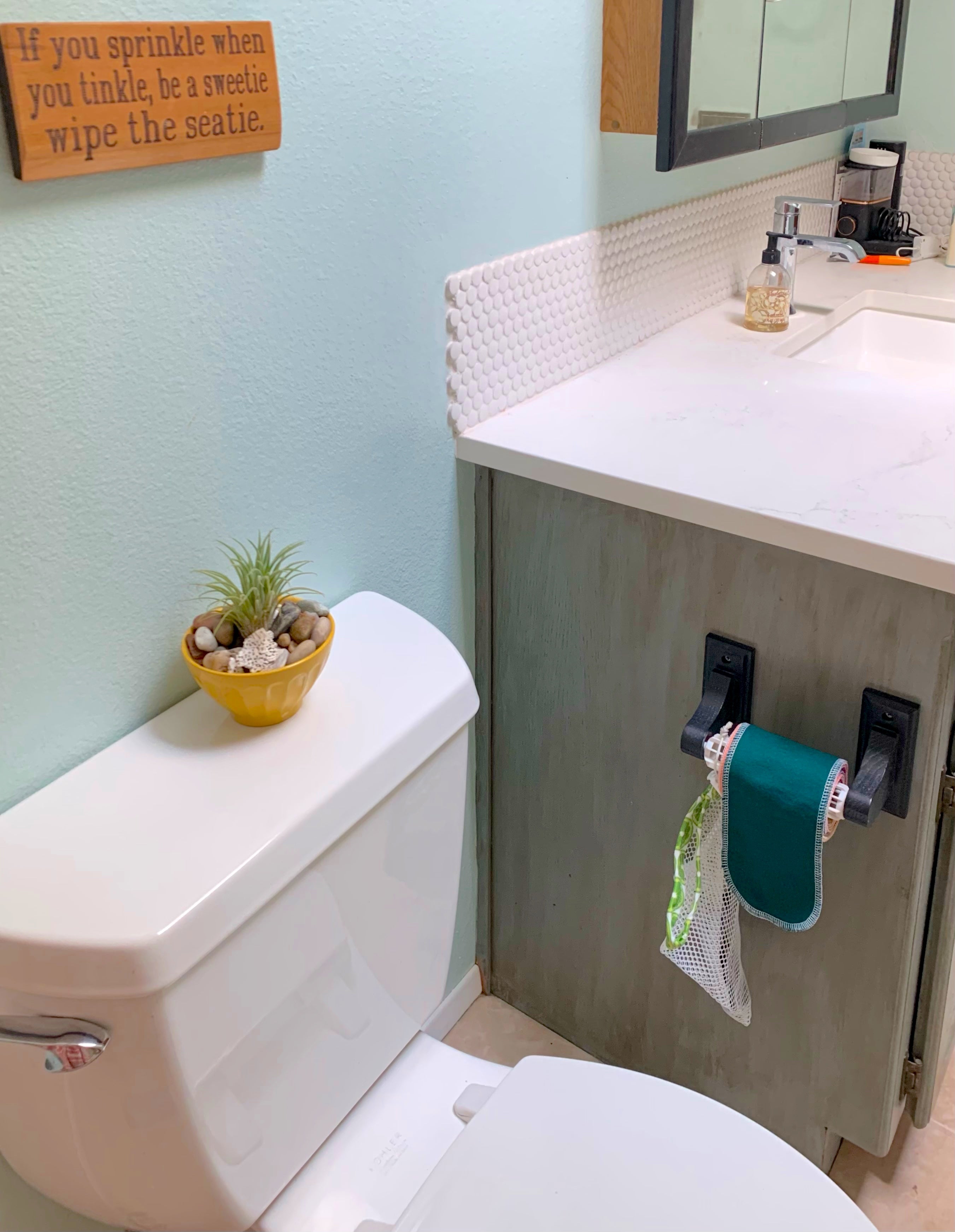 Bathroom with toilet, sink, and decorative elements on a light blue wall.