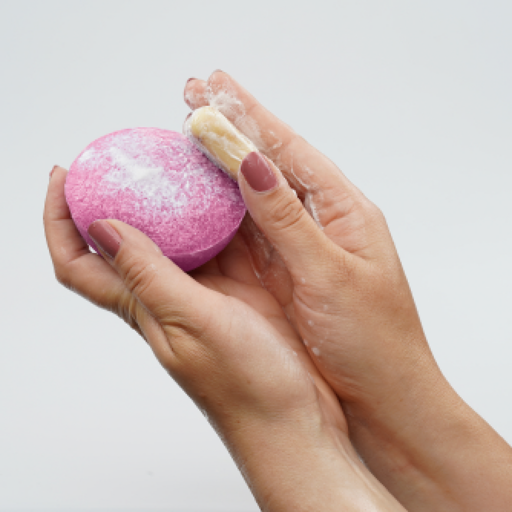 Pink exfoliating sponge being held with a white background