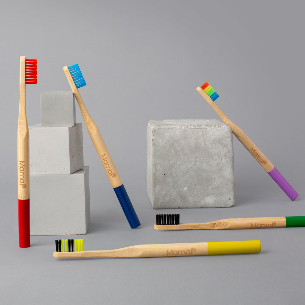 Set of bamboo toothbrushes with colored bristles on a gray background