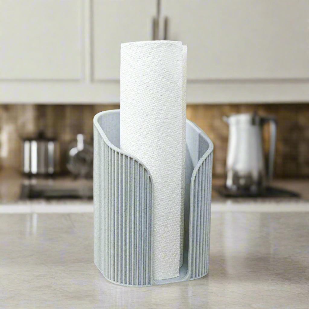 Gray paper towel holder with a roll of paper towels on a kitchen counter.