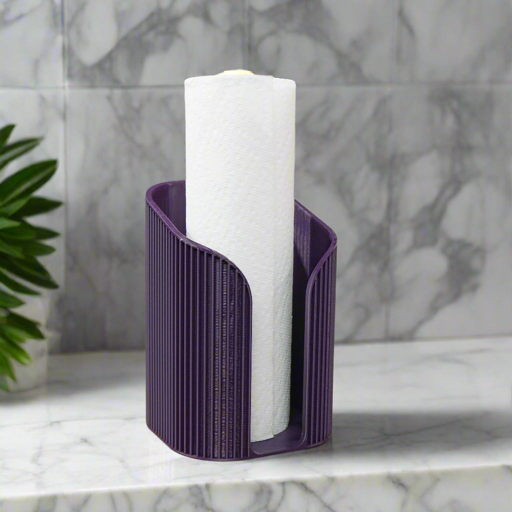 Purple paper towel holder with a roll of paper towels on a marble surface.