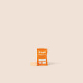 Orange supplement package with a white label on a beige background