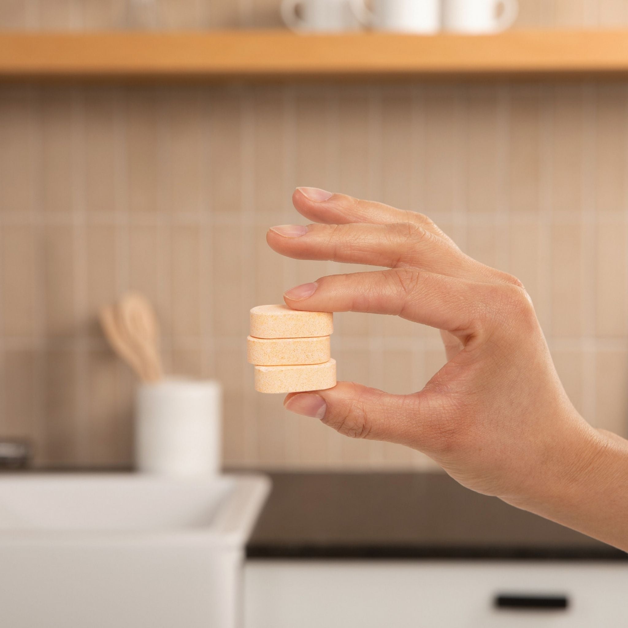 Hand holding a small stack of wooden blocks in a kitchen setting