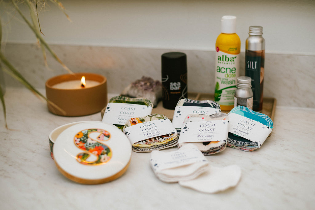 Collection of skincare products and a candle on a bathroom counter.