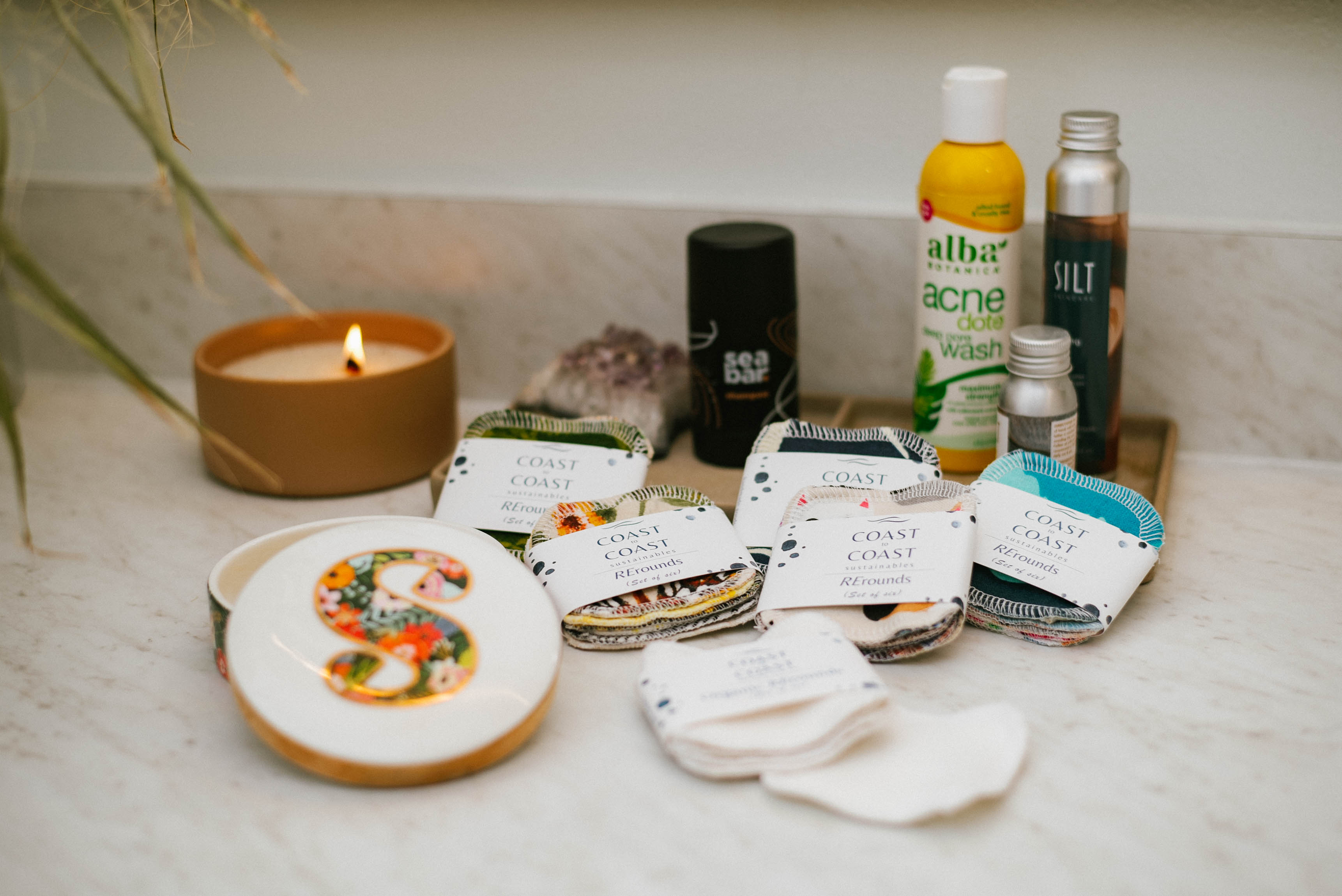 Collection of skincare products and a candle on a bathroom counter.