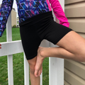 Kid wearing black bamboo cartwheel shorts and colorful long sleeve top