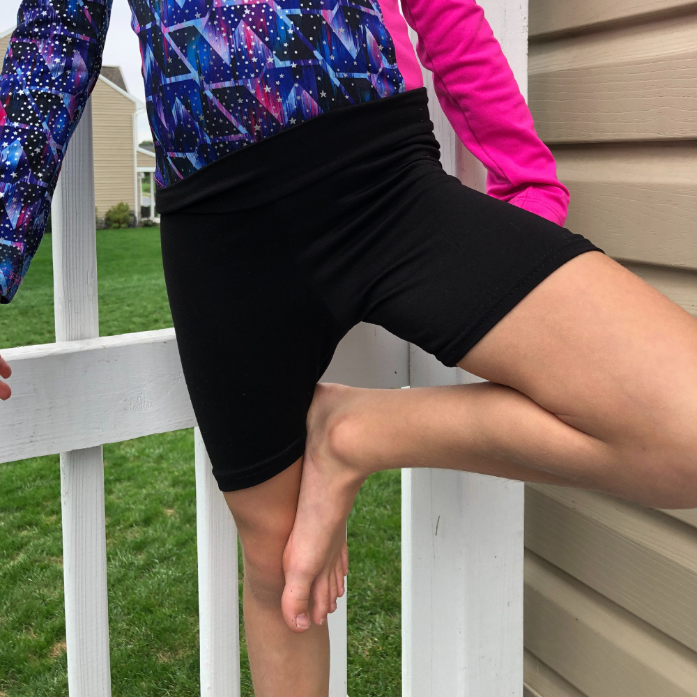 Kid wearing black bamboo cartwheel shorts and colorful long sleeve top