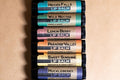 Stack of lip balm tubes with various flavors on a beige background