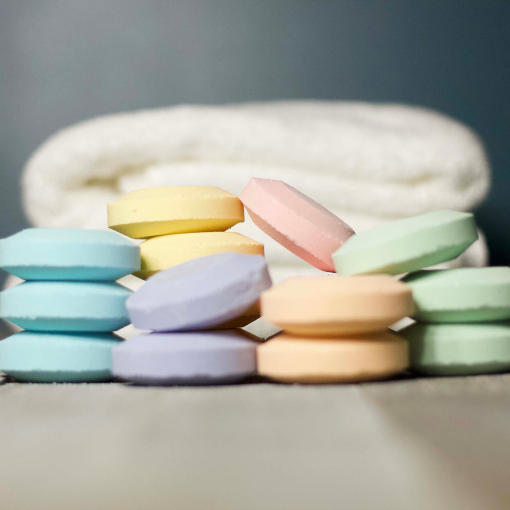 Pastel-colored bath bombs on a gray surface with a blurred background