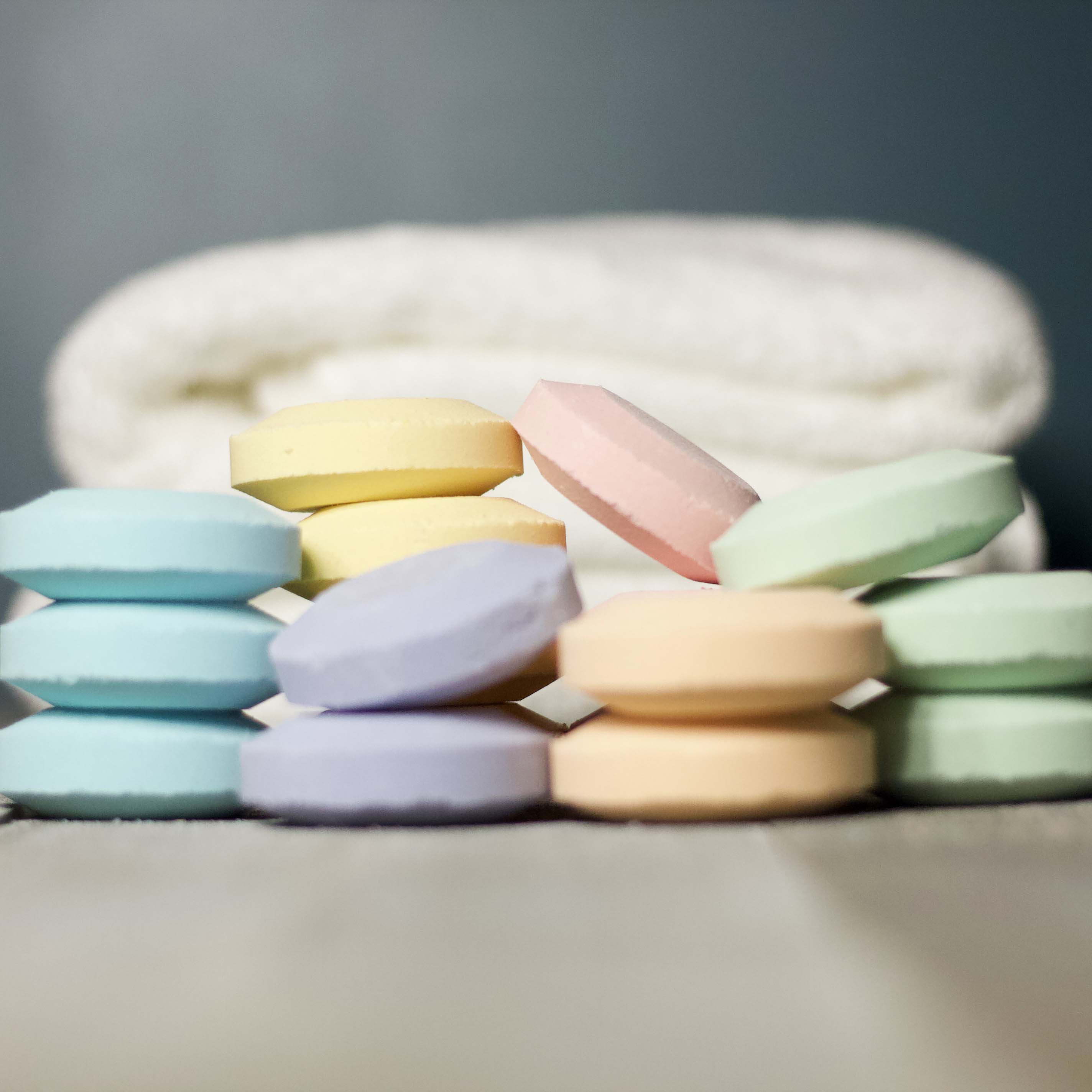 Pastel-colored bath bombs on a gray surface with a blurred background