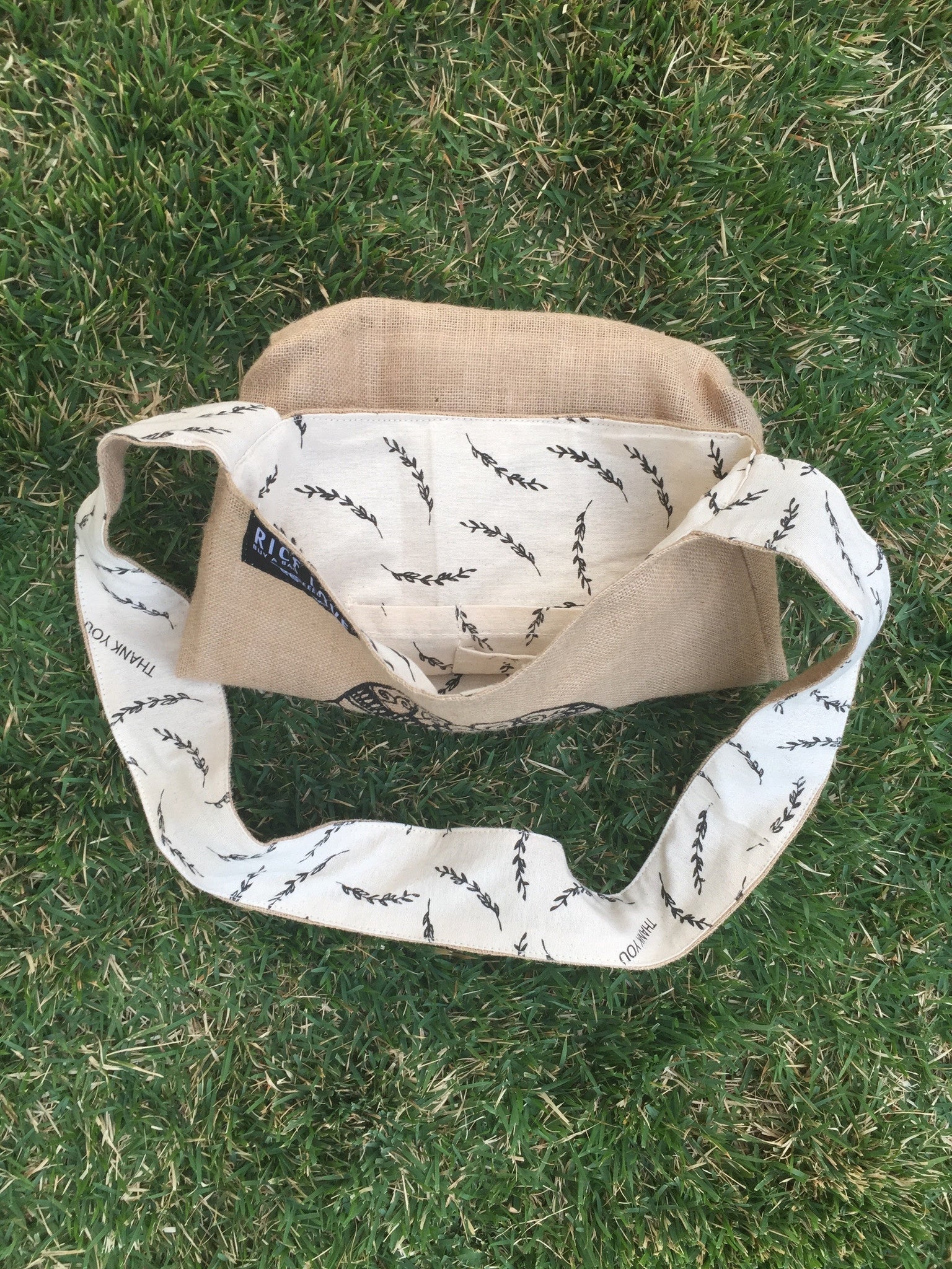 Beige and white bag with black patterns on grass