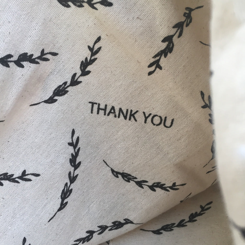 Textile with black leaf patterns and 'THANK YOU' text on a beige background