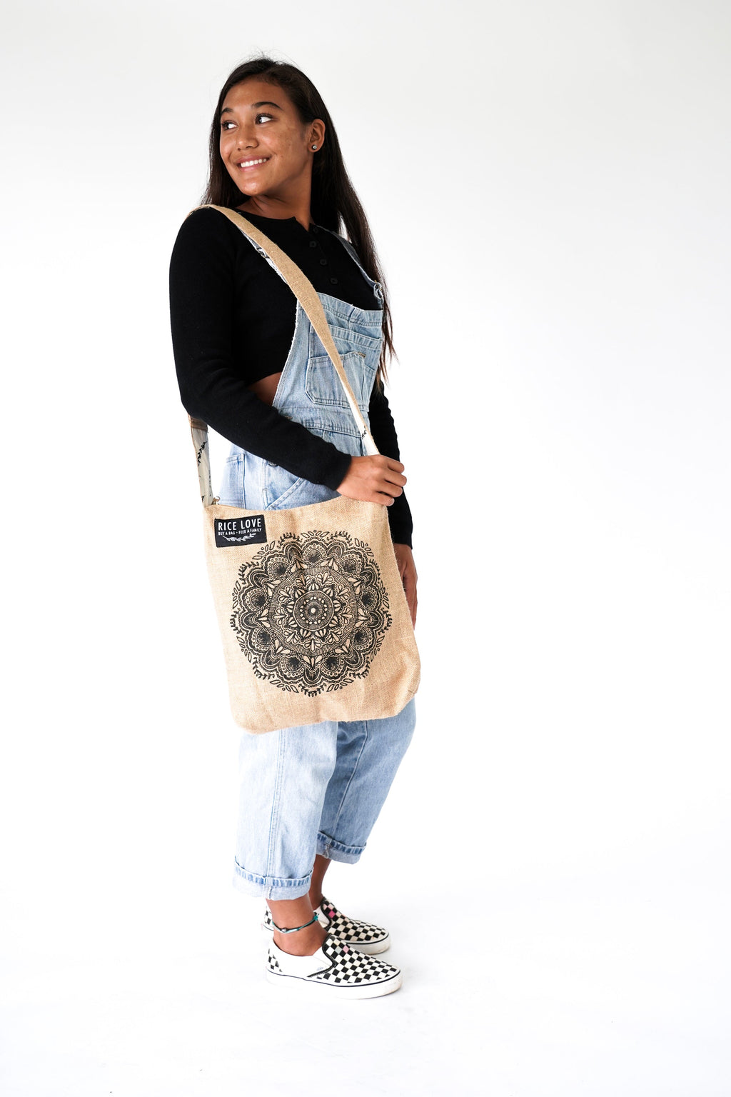 Person holding a beige tote bag with a mandala design on a white background