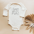 White baby onesie with 'I love you more' text on a beige background