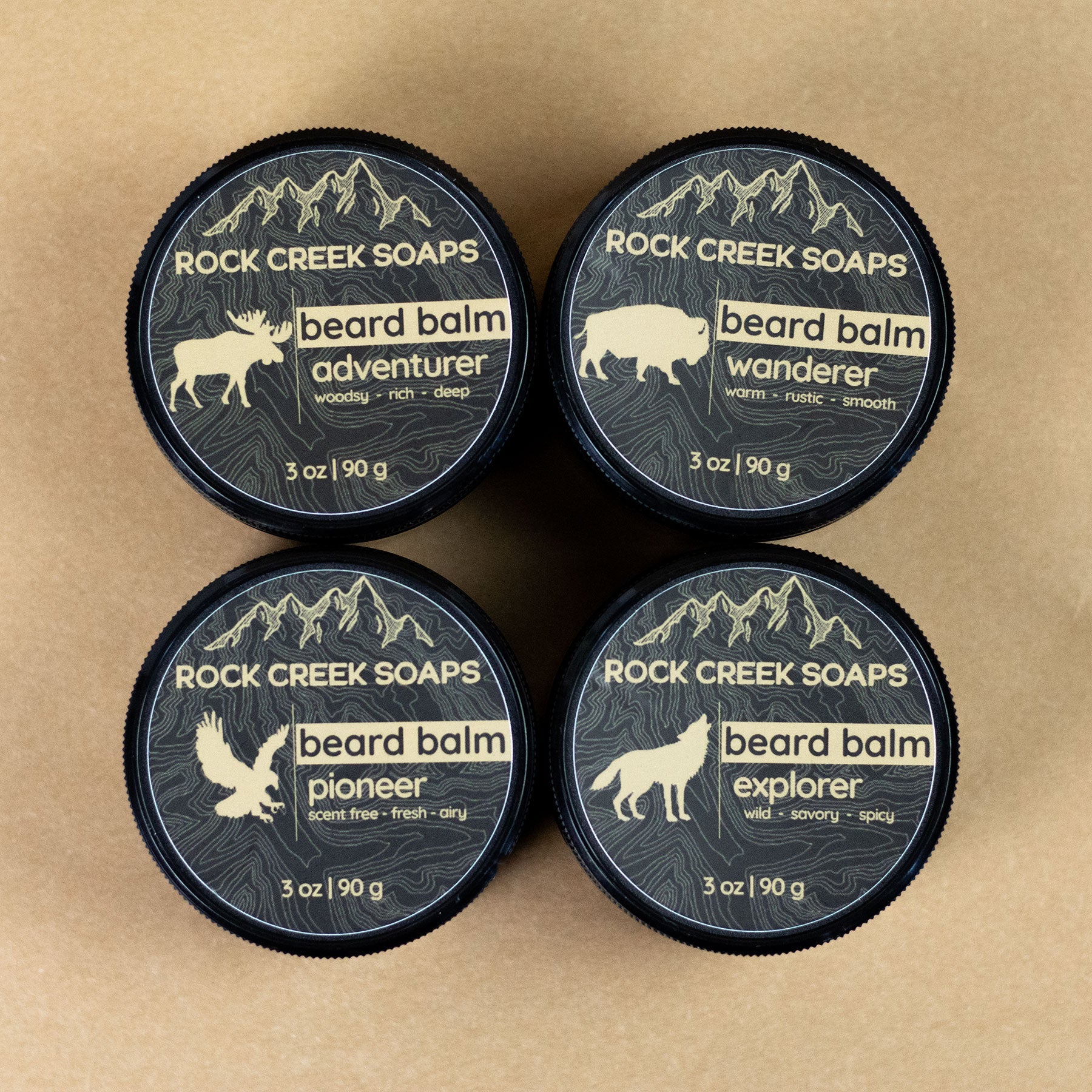 Four containers of Rock Creek Soaps beard balms on a brown background